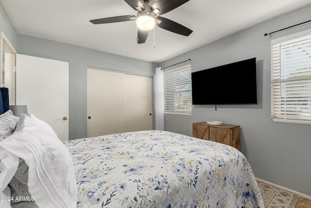 bedroom with multiple windows, a closet, a ceiling fan, and baseboards