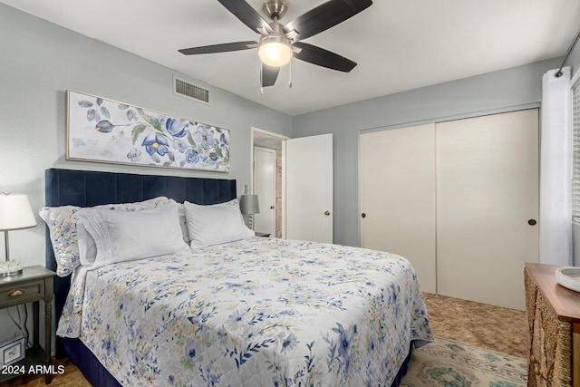 bedroom featuring a ceiling fan, visible vents, dark carpet, and a closet