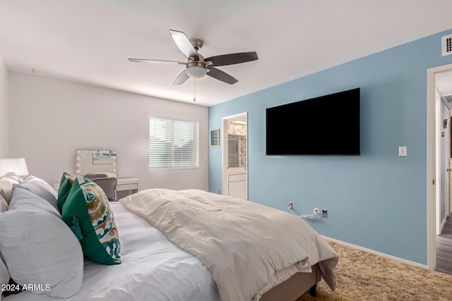 carpeted bedroom featuring a ceiling fan, ensuite bath, and baseboards