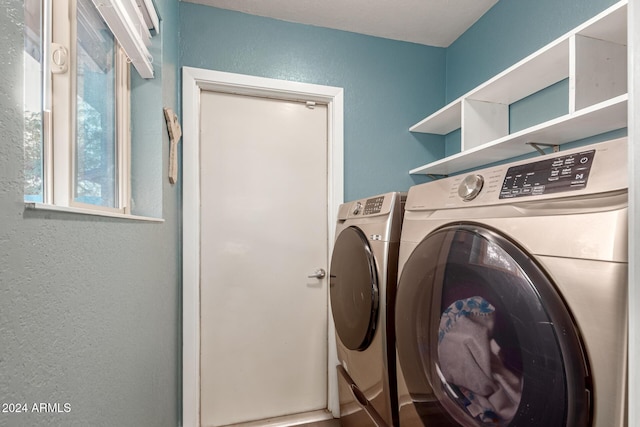 clothes washing area featuring a textured wall, laundry area, and washing machine and clothes dryer