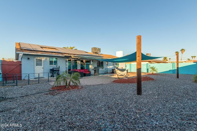 back of property featuring a patio area, outdoor lounge area, a fenced backyard, and solar panels