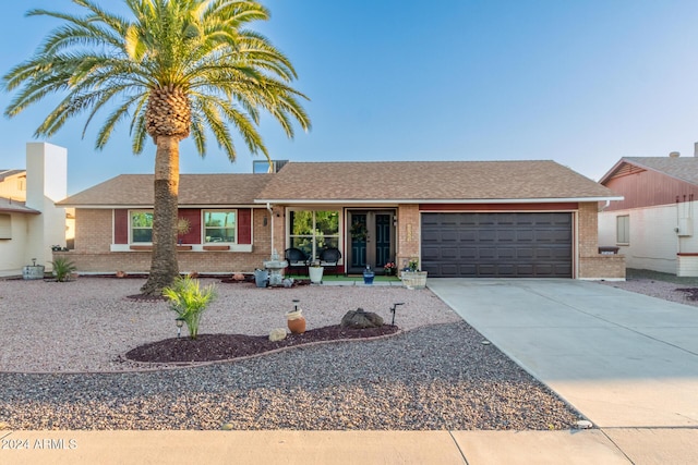 ranch-style house featuring a shingled roof, brick siding, driveway, and an attached garage