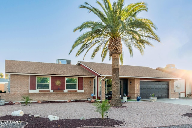 ranch-style house with driveway, an attached garage, roof with shingles, and brick siding