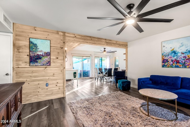 living room featuring wooden walls, visible vents, and dark wood finished floors