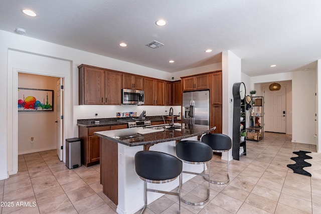 kitchen with visible vents, a breakfast bar, a sink, appliances with stainless steel finishes, and light tile patterned floors