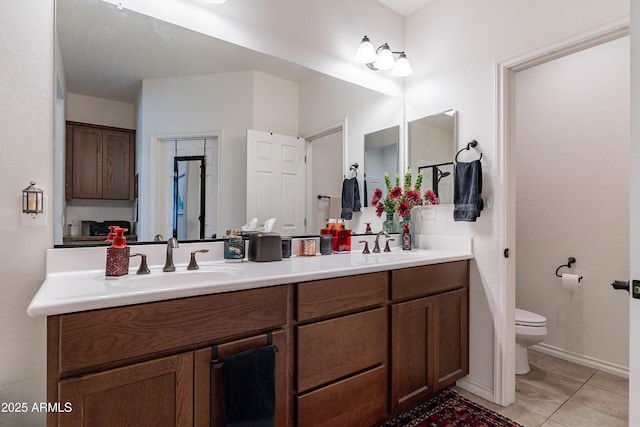 full bath with a sink, tile patterned floors, toilet, and double vanity