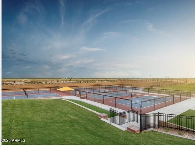 view of tennis court featuring fence and a yard
