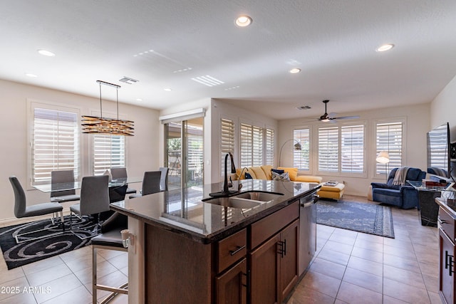 kitchen featuring a sink, a ceiling fan, light tile patterned floors, and a kitchen bar