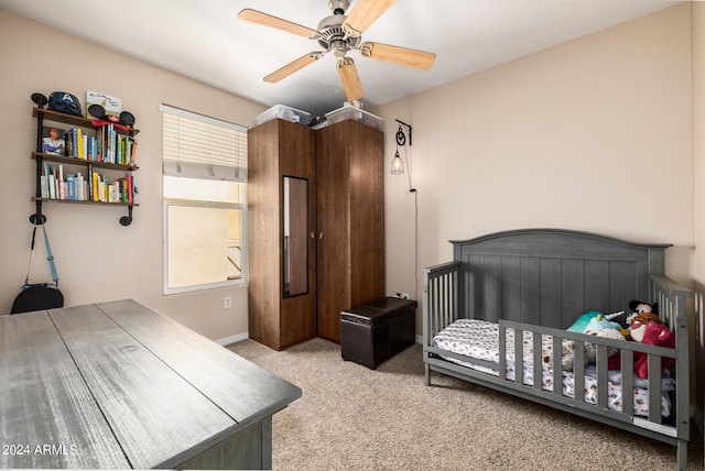 carpeted bedroom with ceiling fan and a nursery area