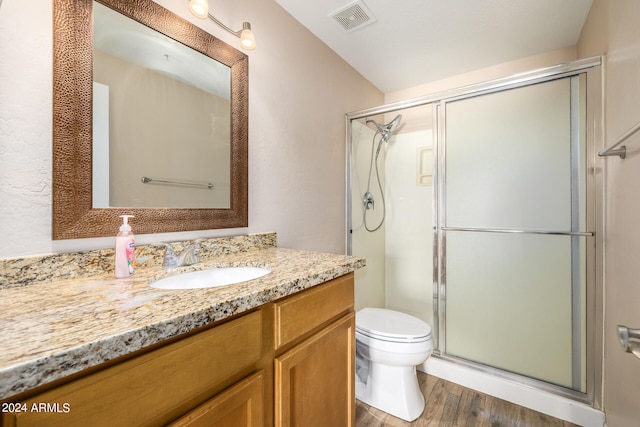 bathroom with hardwood / wood-style floors, vanity, toilet, and a shower with shower door