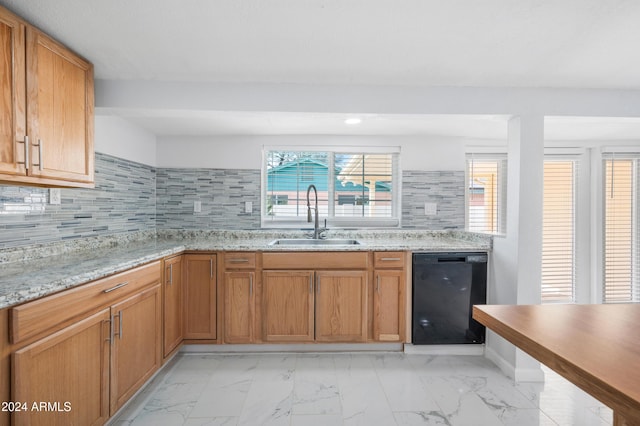 kitchen with tasteful backsplash, light stone countertops, sink, and black dishwasher