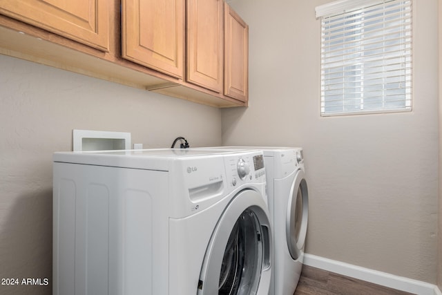 clothes washing area with dark wood-type flooring, cabinets, and washer and dryer