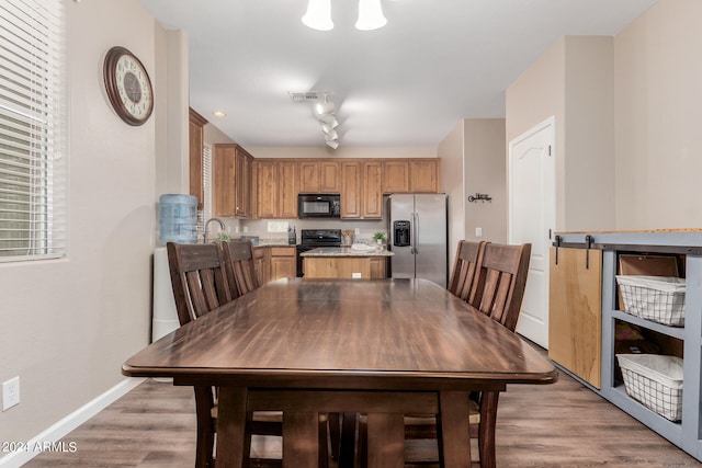 dining area with sink, track lighting, and light hardwood / wood-style floors