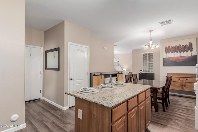 kitchen with light stone counters, a notable chandelier, a center island, pendant lighting, and dark hardwood / wood-style flooring