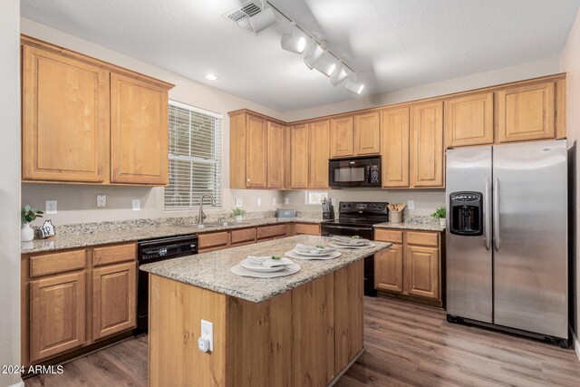 kitchen with black appliances, dark hardwood / wood-style flooring, light stone countertops, sink, and a center island