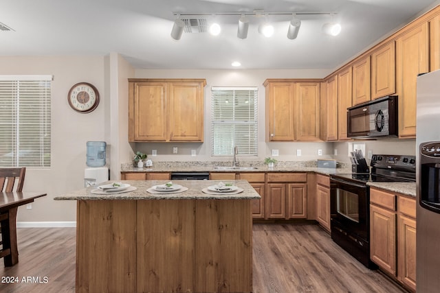 kitchen featuring hardwood / wood-style floors, black appliances, sink, and a center island