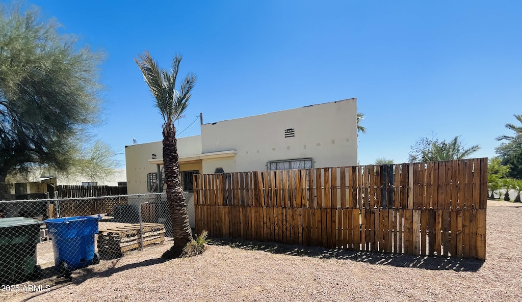view of side of home featuring fence, stucco siding, and central air condition unit