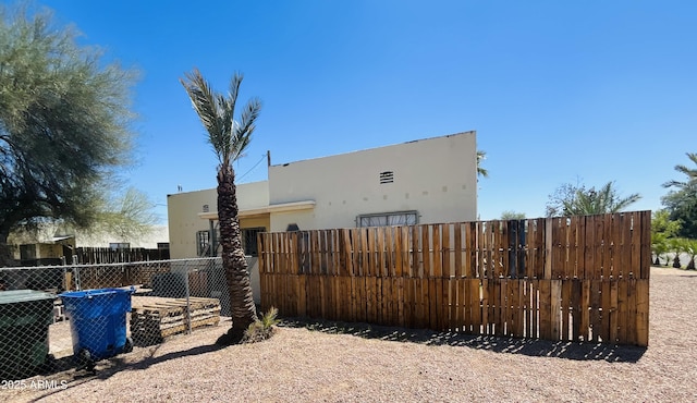 view of side of home featuring fence, stucco siding, and central air condition unit