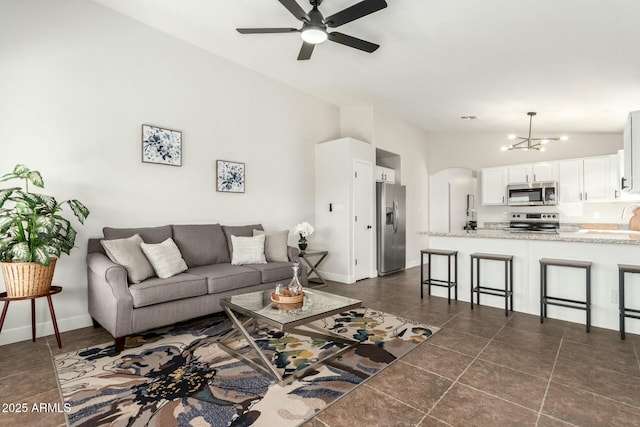 living room featuring sink, lofted ceiling, dark tile patterned flooring, and ceiling fan with notable chandelier