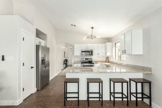 kitchen with lofted ceiling, white cabinetry, a kitchen breakfast bar, stainless steel appliances, and kitchen peninsula