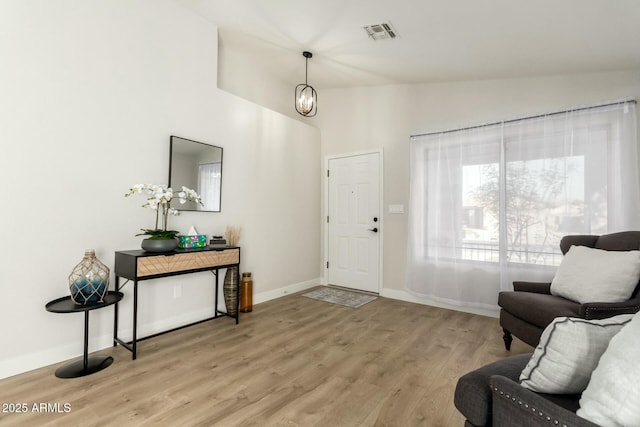 entryway featuring lofted ceiling, a chandelier, and light hardwood / wood-style floors