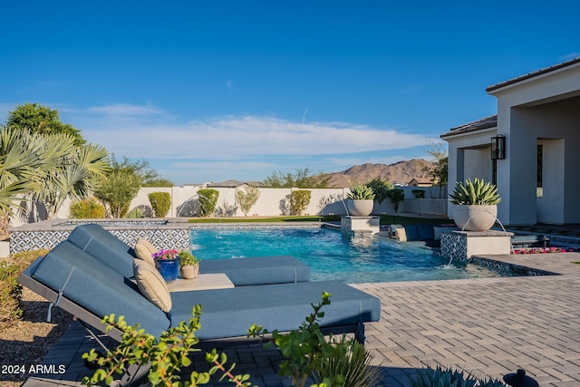 view of swimming pool with a patio area, a mountain view, and pool water feature