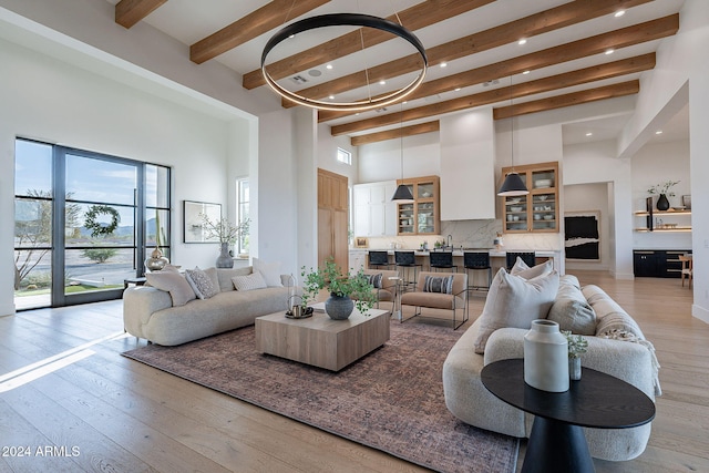 living room with light hardwood / wood-style floors, beam ceiling, and a high ceiling