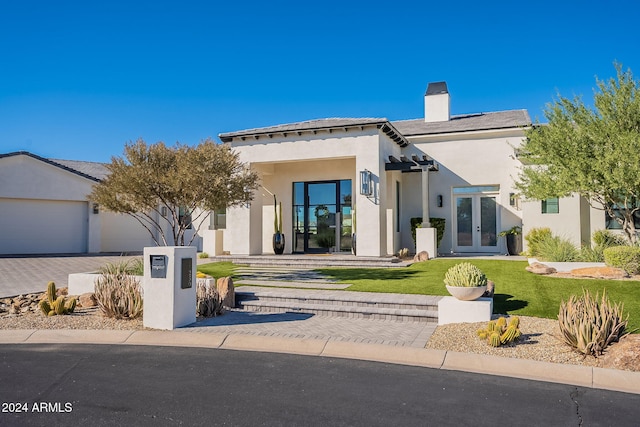 view of front of property with a front yard, french doors, and a garage