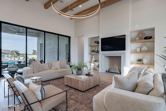 living room featuring a towering ceiling, beamed ceiling, dark hardwood / wood-style floors, and built in features