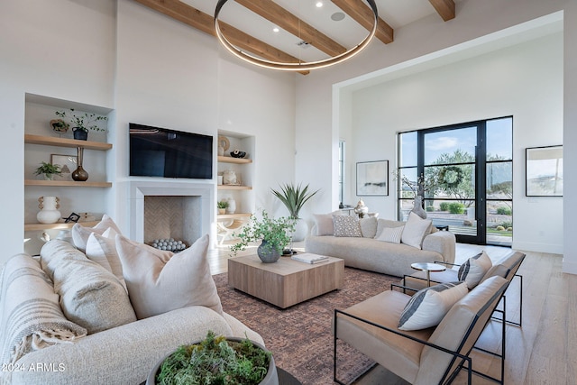 living room featuring hardwood / wood-style floors, beam ceiling, a high ceiling, and built in shelves