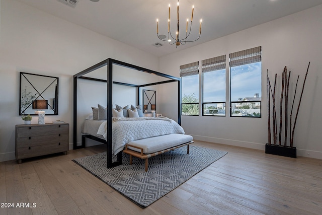 bedroom with light hardwood / wood-style floors and an inviting chandelier