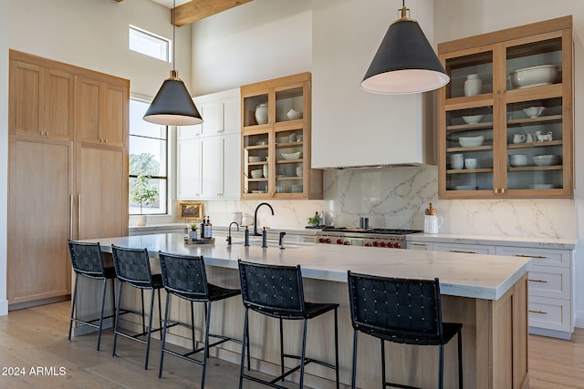 kitchen with a wealth of natural light, white cabinets, hanging light fixtures, and a center island with sink