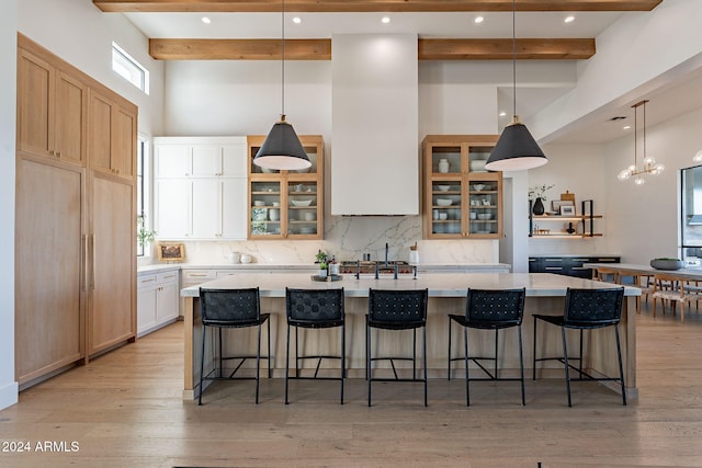 kitchen with a large island, beamed ceiling, a breakfast bar, and light wood-type flooring