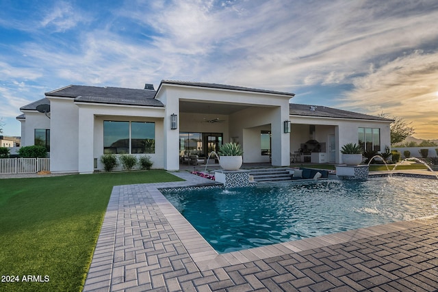 rear view of house featuring pool water feature, a lawn, a patio area, a fenced in pool, and ceiling fan