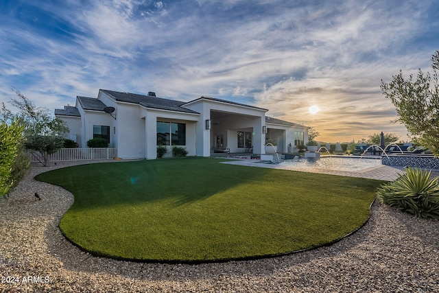 back house at dusk with a yard, pool water feature, and a patio area