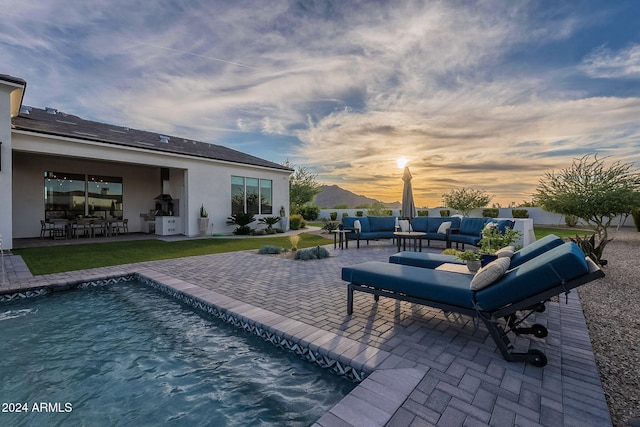 pool at dusk featuring a patio and an outdoor hangout area