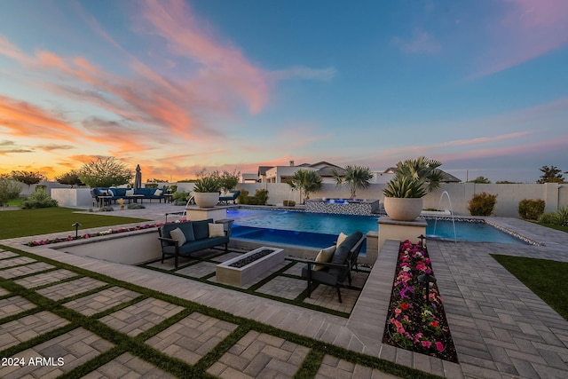 pool at dusk with a patio, pool water feature, and a lawn