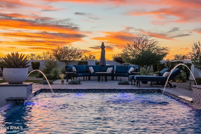 pool at dusk with a patio area, pool water feature, and outdoor lounge area