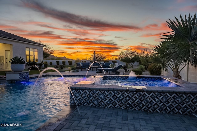 pool at dusk featuring pool water feature and a patio