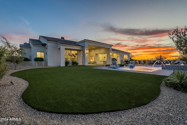 back house at dusk featuring a patio area, pool water feature, and a lawn