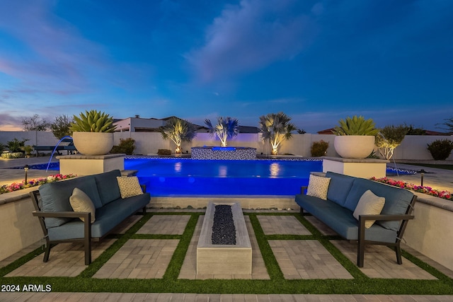 pool at dusk with a patio area, pool water feature, and an outdoor living space