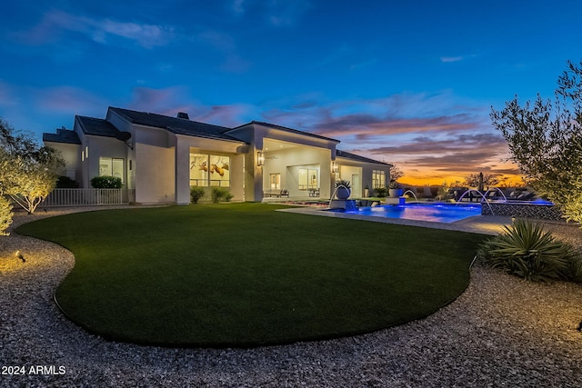 back house at dusk with a patio area, pool water feature, and a yard