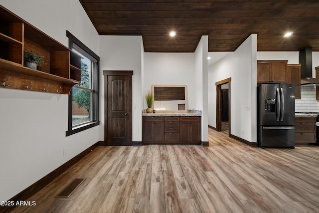 2702 Majestic Elk Rd, Overgaard, AZ 85933 - kitchen featuring visible vents, baseboards, wall chimney exhaust hood, black fridge, and light wood-style floors