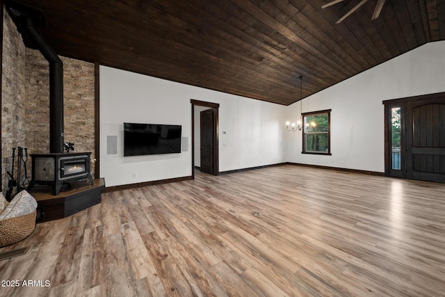 2702 Majestic Elk Rd, Overgaard, AZ 85933 - unfurnished living room featuring baseboards, a chandelier, a wood stove, high vaulted ceiling, and wood finished floors