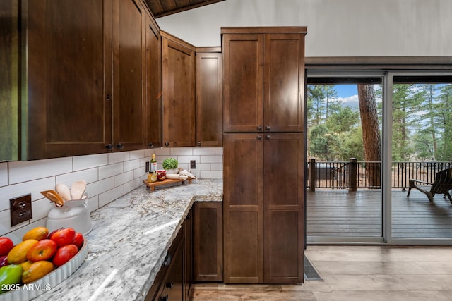 2702 Majestic Elk Rd, Overgaard, AZ 85933 - kitchen featuring light wood-style flooring, decorative backsplash, light stone counters, and lofted ceiling