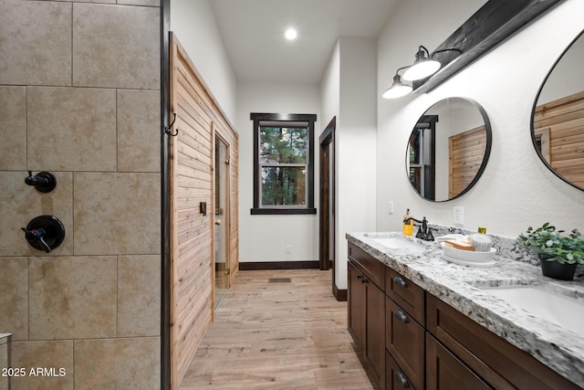 2702 Majestic Elk Rd, Overgaard, AZ 85933 - bathroom featuring baseboards, a sink, double vanity, wood finished floors, and tiled shower