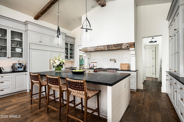 kitchen featuring beamed ceiling, dark countertops, and dark wood finished floors