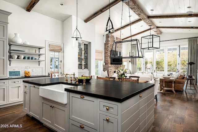 kitchen with dark countertops, open floor plan, and a sink