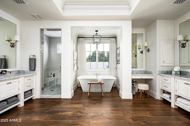 full bath featuring ornamental molding, a freestanding tub, a shower stall, and wood finished floors