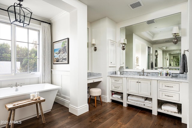 bathroom featuring a soaking tub, visible vents, ornamental molding, wainscoting, and wood finished floors